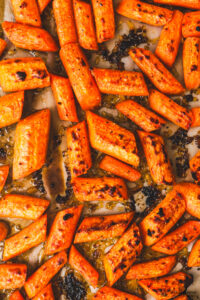 Close up of chopped cooked carrots some charred, with a spinkle of garlic and fresh parsley