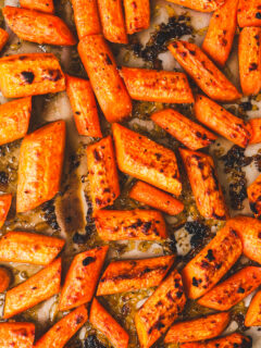 Close up of chopped cooked carrots some charred, with a spinkle of garlic and fresh parsley