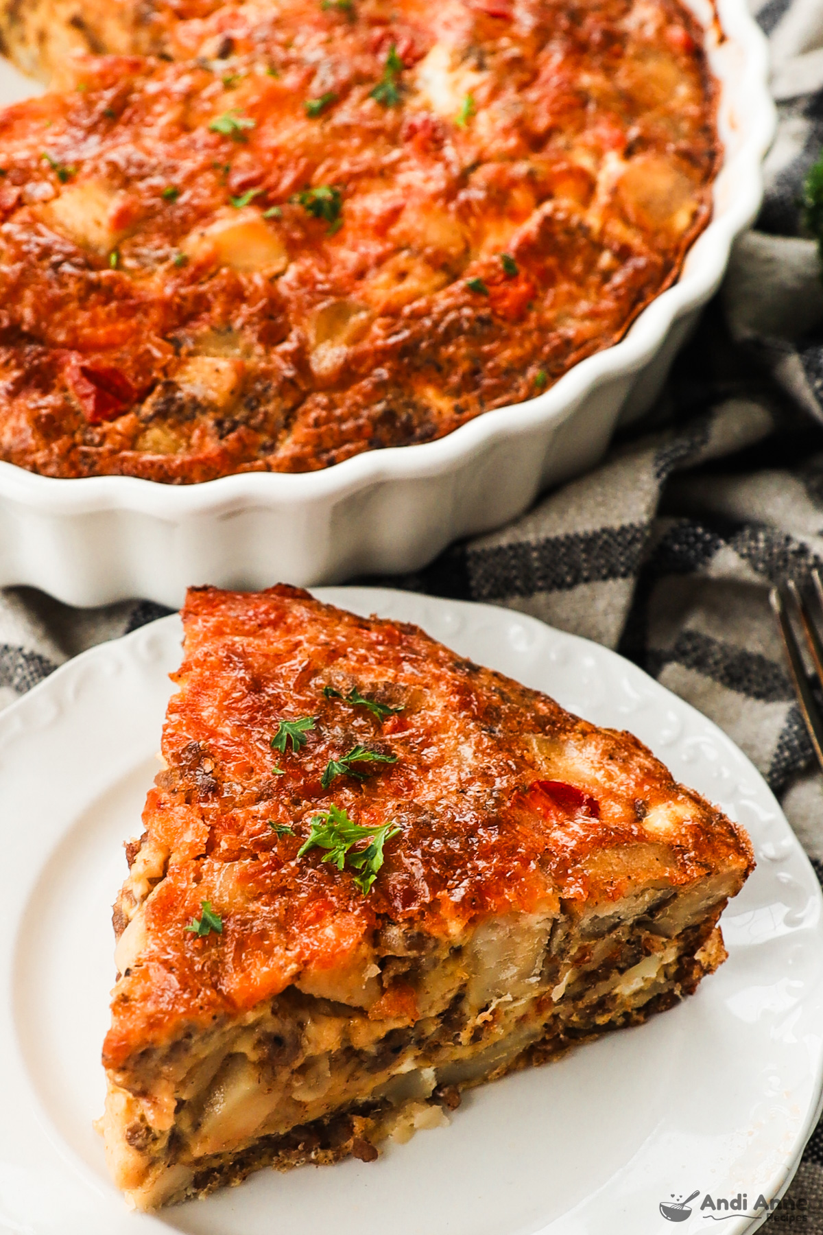 Slice of frittata on a plate with rest of frittata in pan in background