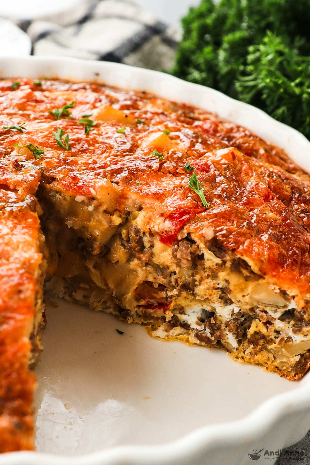 Close up of a frittata with a slice cut out and looking at the side of the frittata