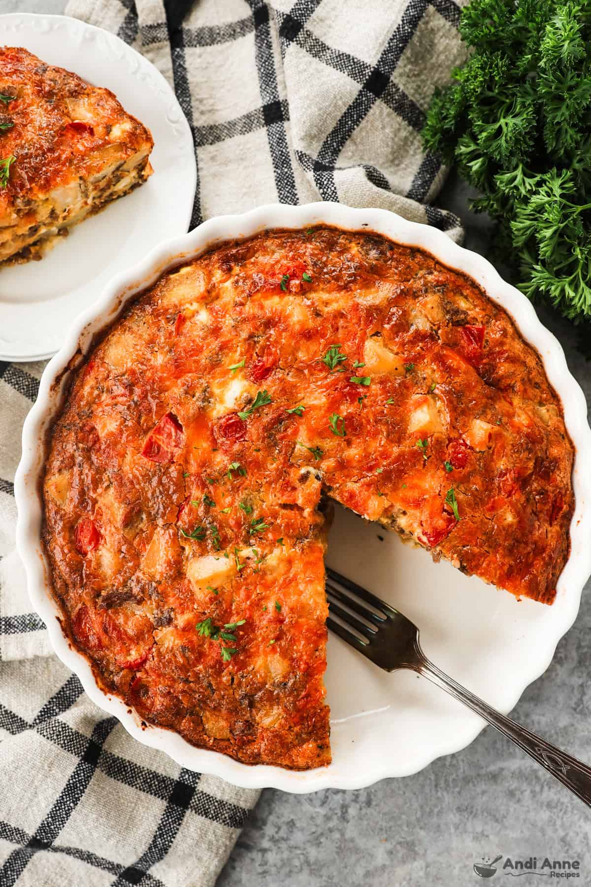 A sausage potato frittata with a slice cut out and a fork