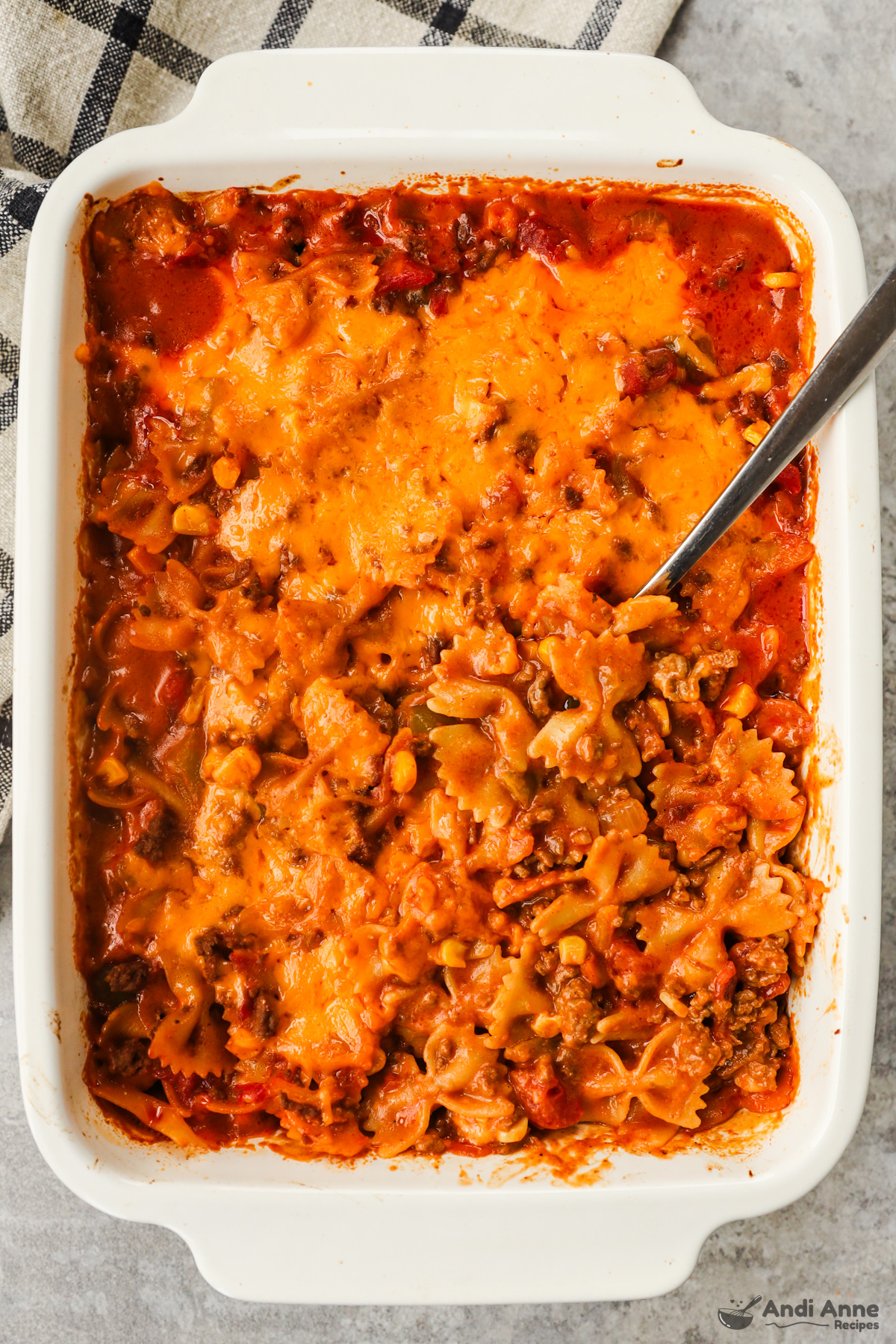 Casserole dish with cooked sloppy joe recipe with bowtie pasta, ground beef and cheese in a creamy sauce.