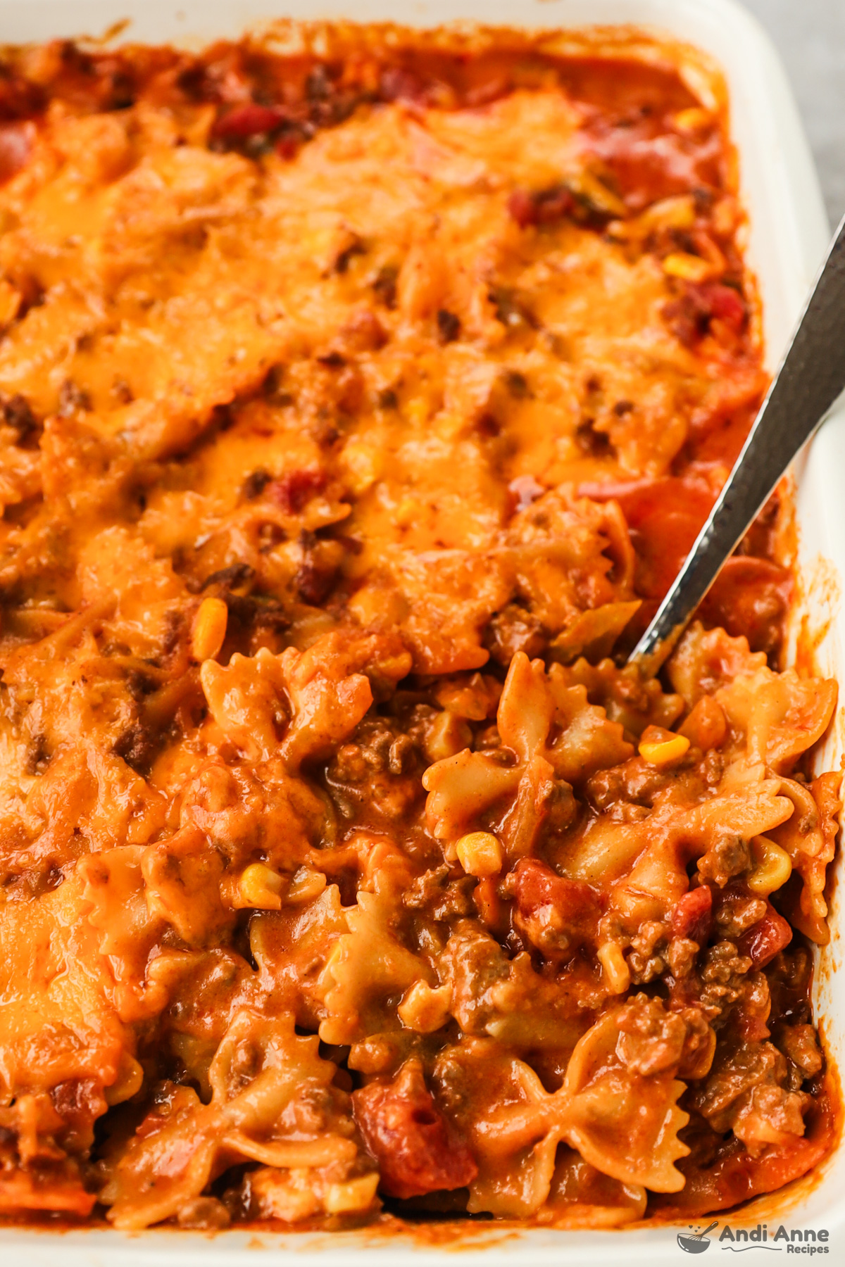 Close up of bowtie pasta with ground beef tomatoes and corn in casserole.