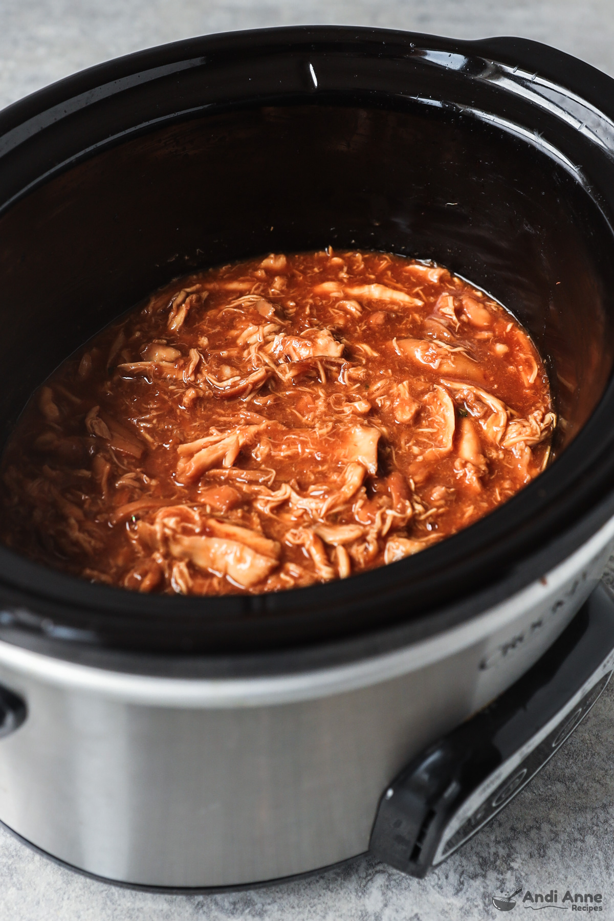 Slow cooker with shredded honey garlic chicken inside