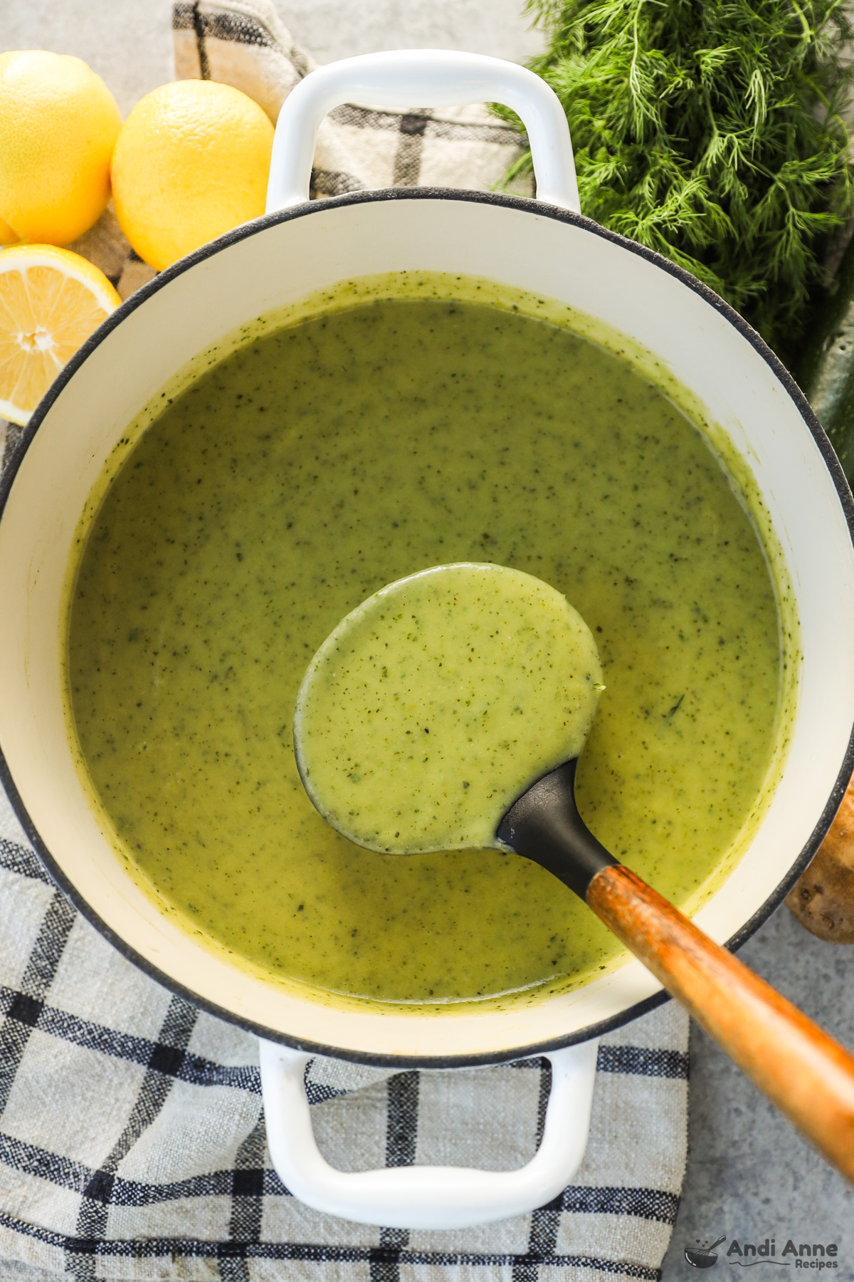 A pot of creamy zucchini soup with a soup ladle holding a big scoop.