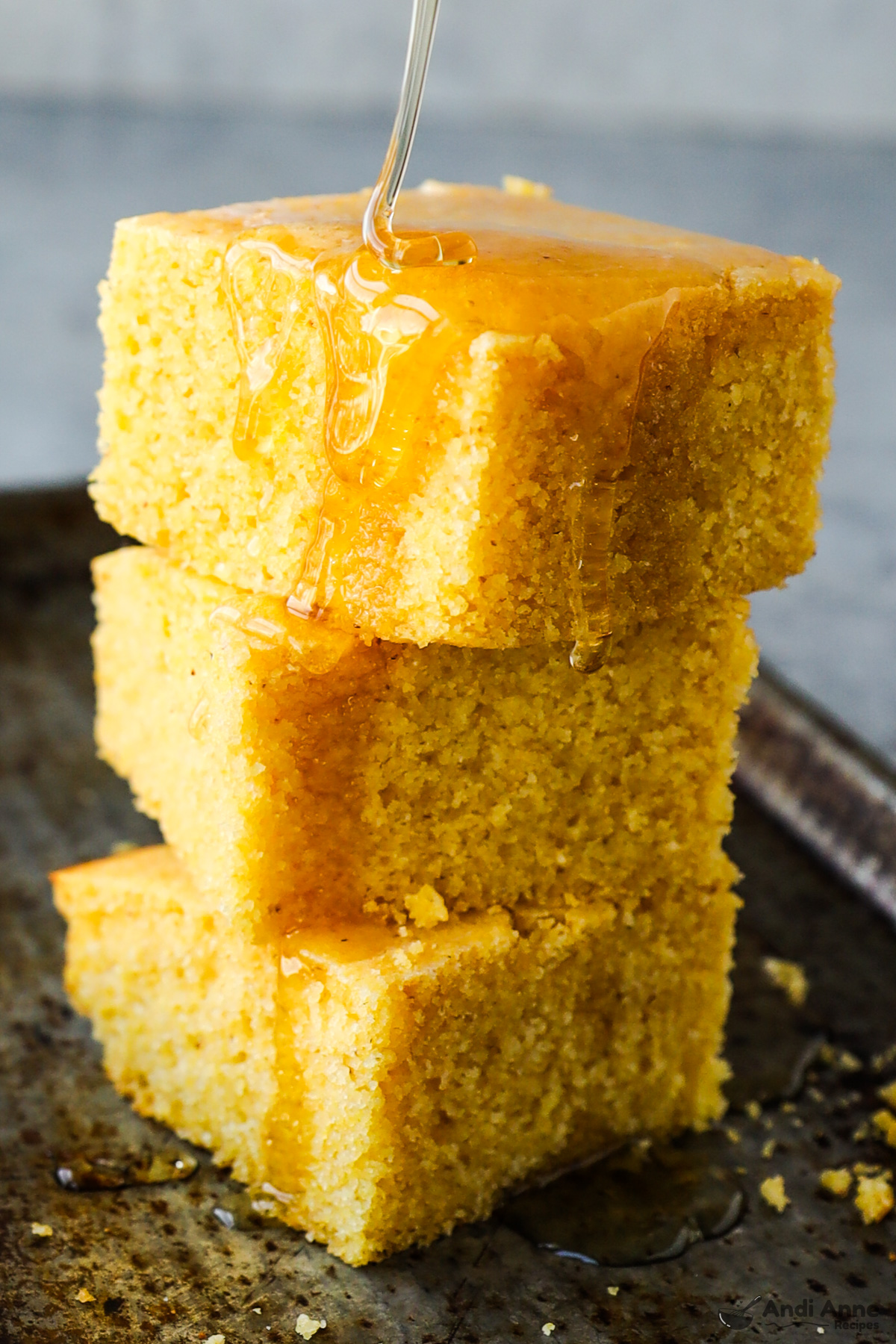 A stack of cornbread pieces drizzled with honey