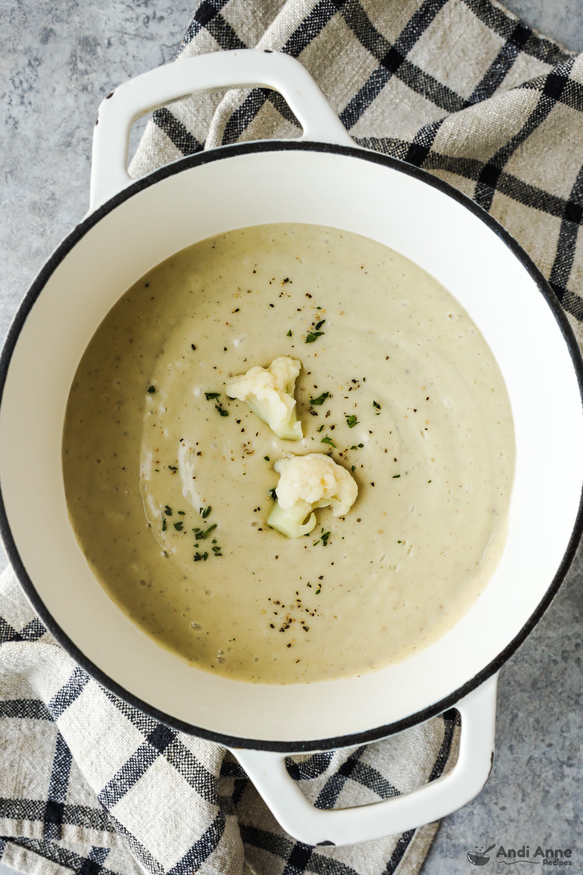 A bowl of creamy cauliflower soup with two pieces of cauliflower on top