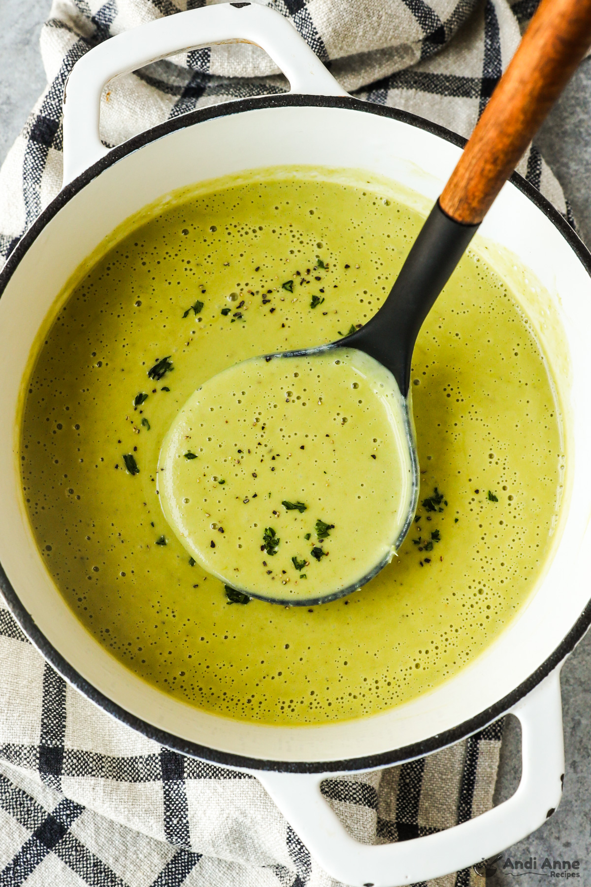 A bowl of creamy asparagus soup with a soup ladle