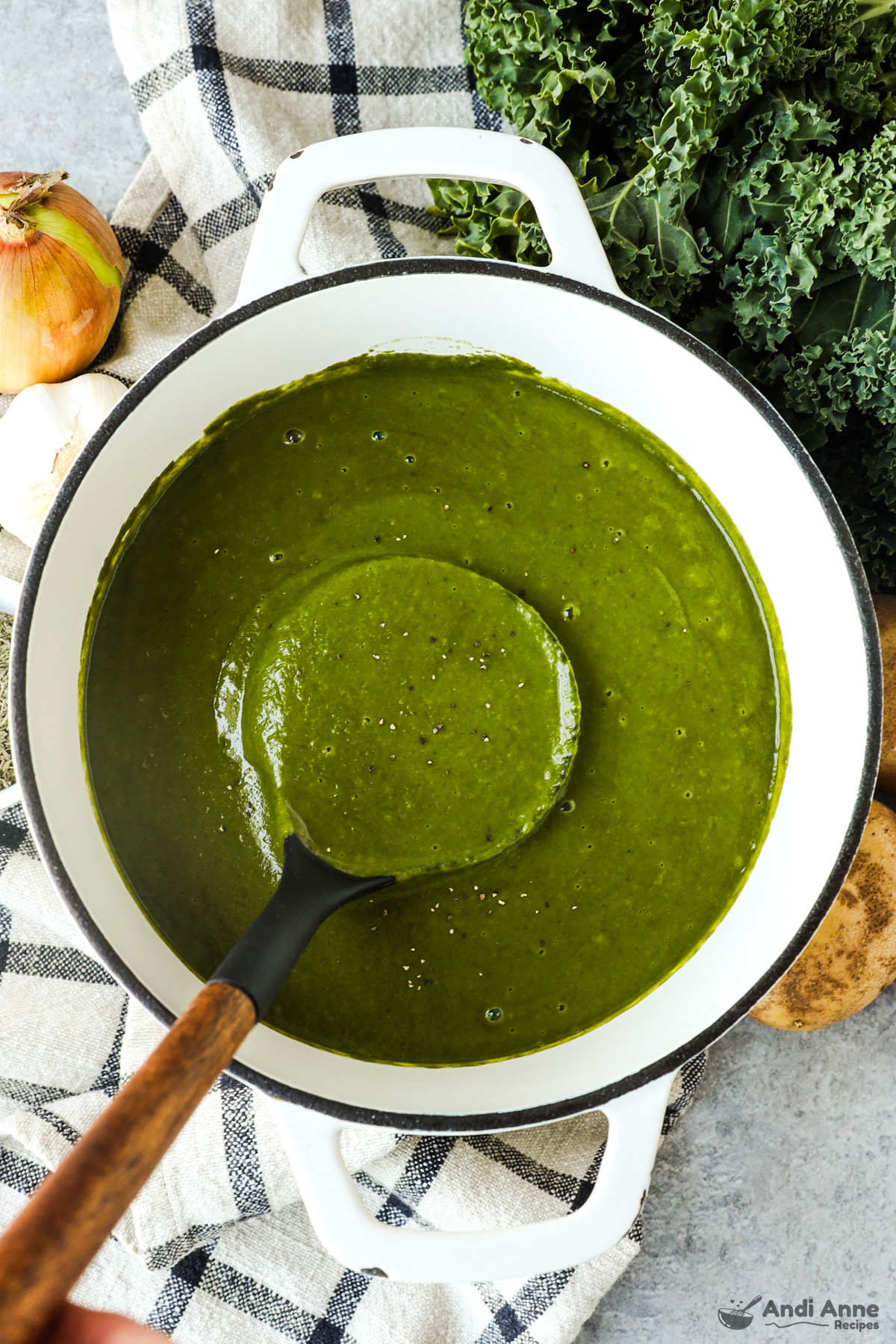 A bowl of creamy kale soup with a soup ladle