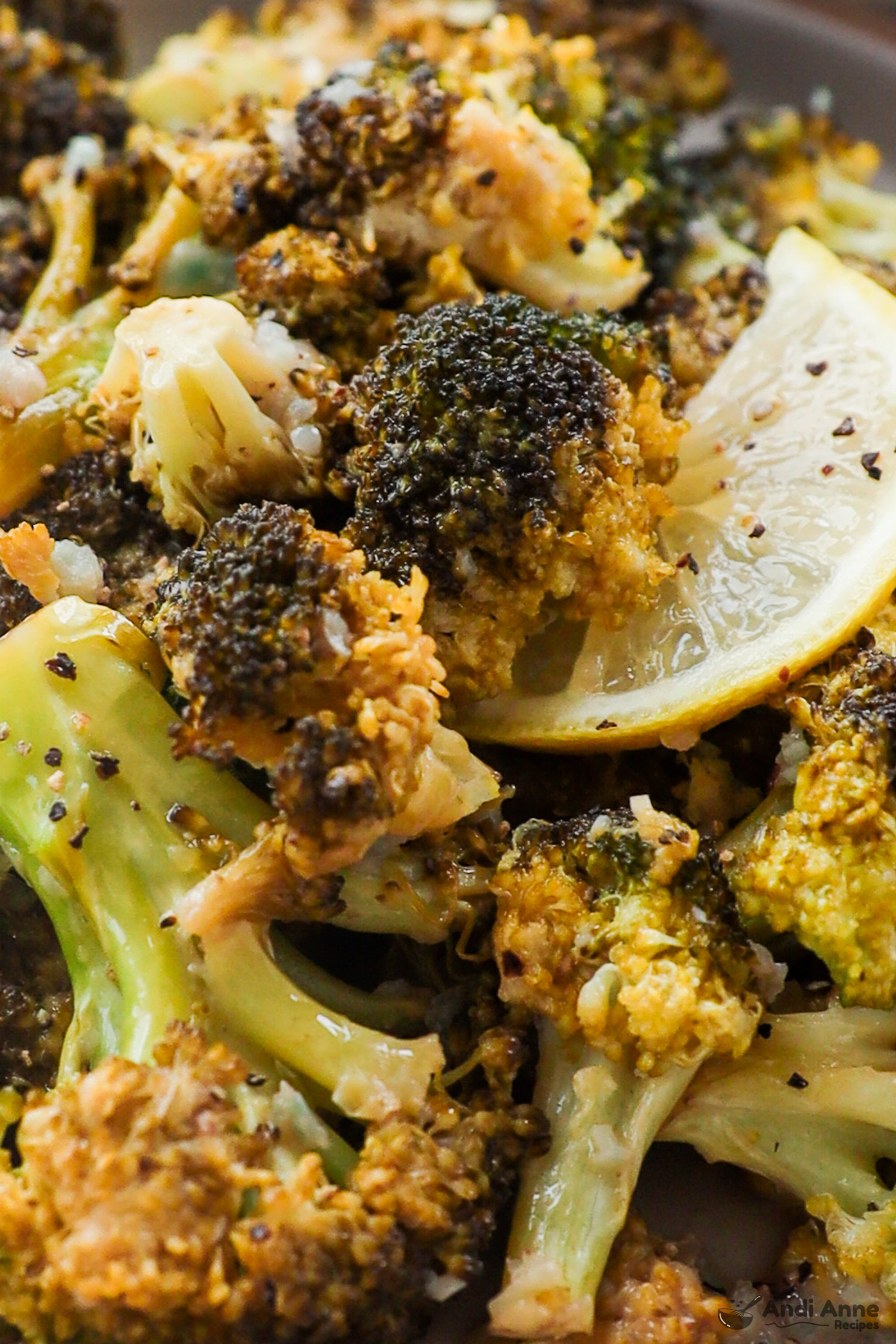 Close up of lemon garlic broccoli and a lemon slice