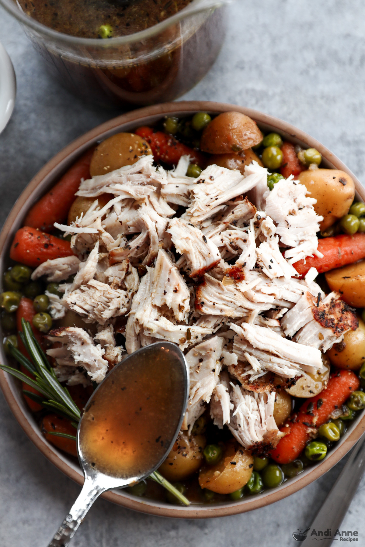 shredded pork over cooked peas, carrots and corn with a spoon of broth over top