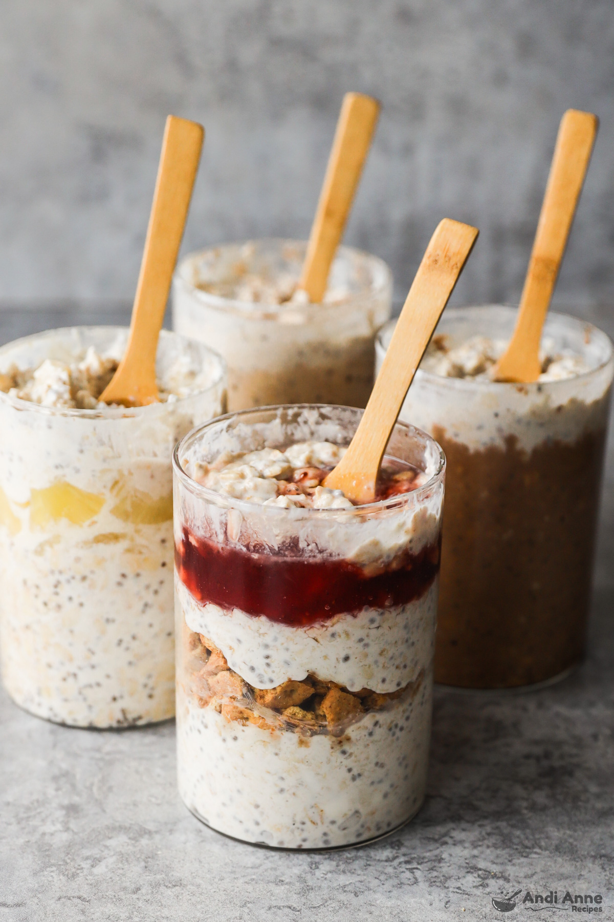 Four jars of overnight oats in different flavors with wood spoons sticking in