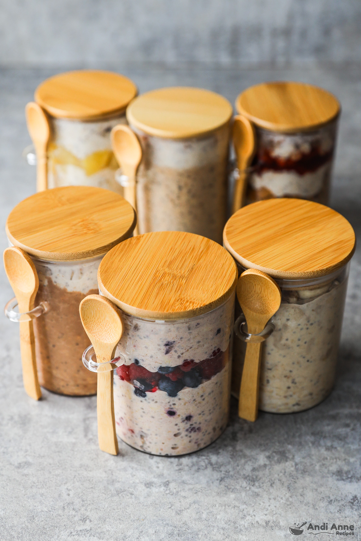 Jars of overnight oats with wood spoons and wood lids