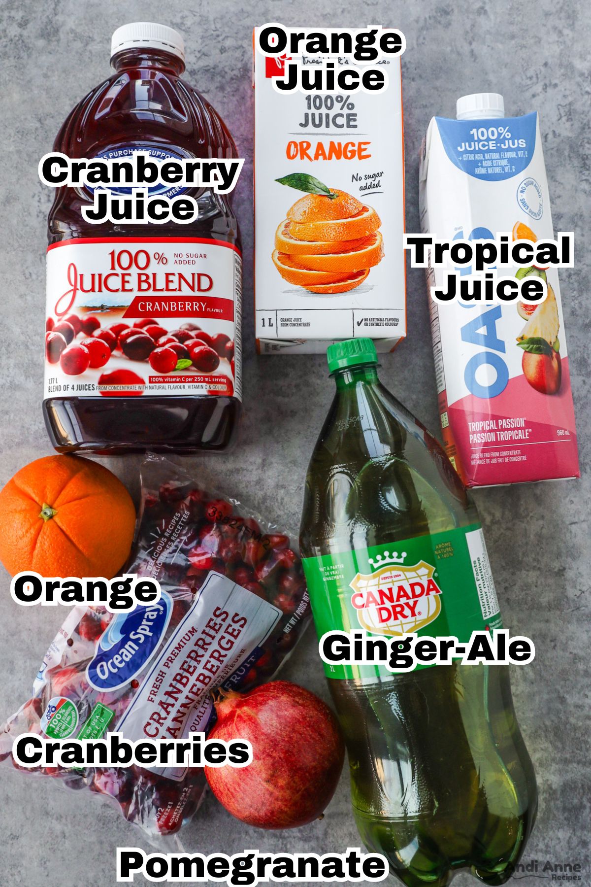 Recipe ingredients including containers of cranberry juice, orange juice, tropical juice, ginger ale, a navel orange, a pomegranate, bag of cranberries