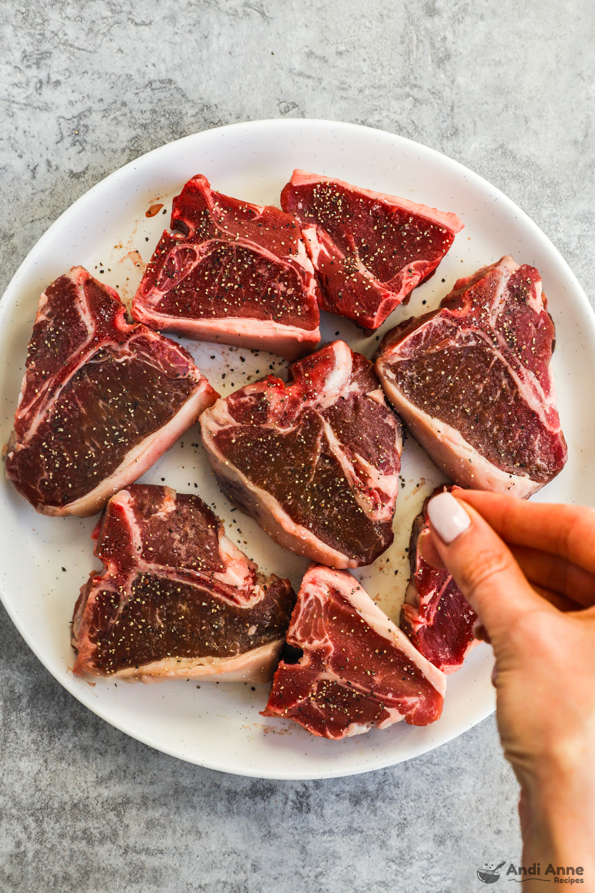 A plate of raw lamb chops seasoned with salt and pepper