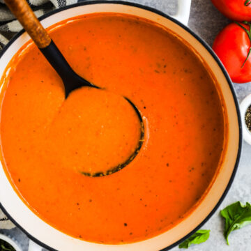 A pot of tomato soup with soup ladle