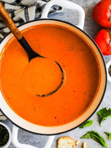 A pot of tomato soup with soup ladle