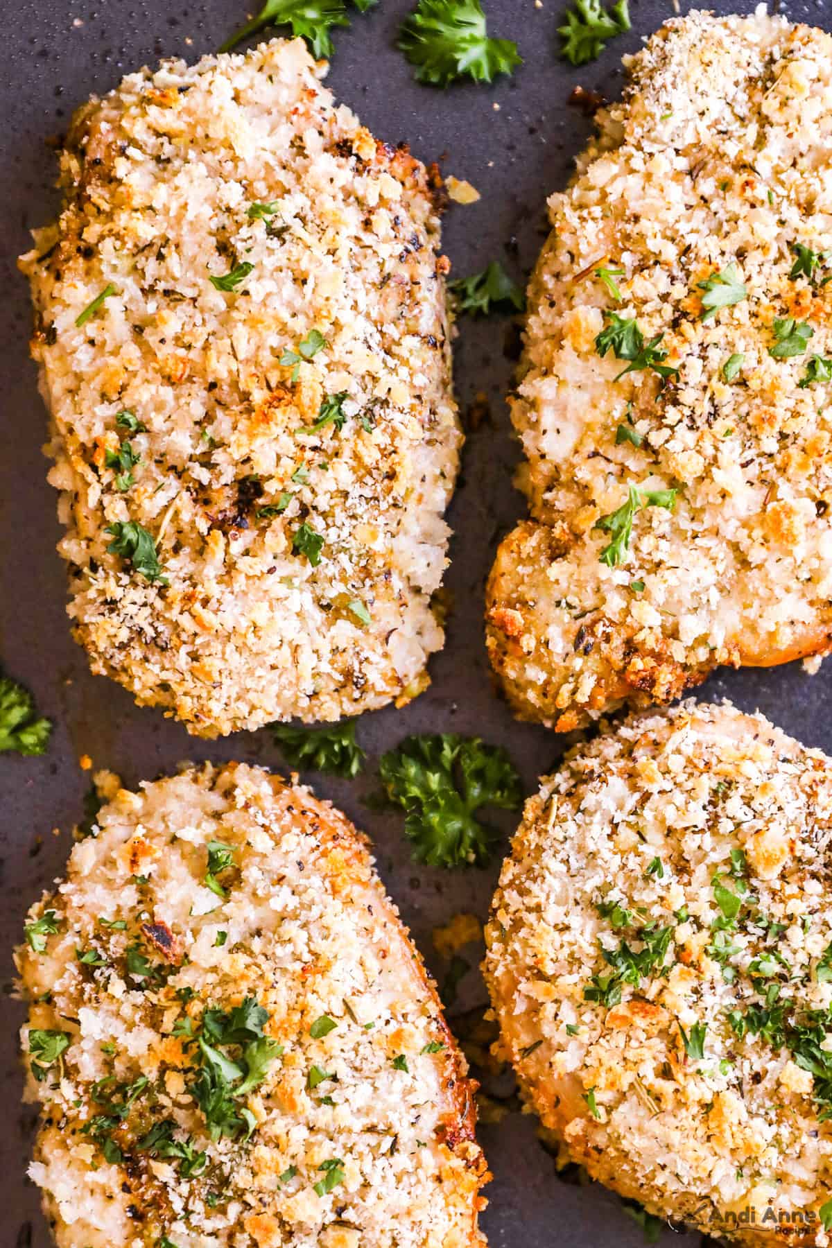 Close up of breaded pork chops with a sprinkle of parsley