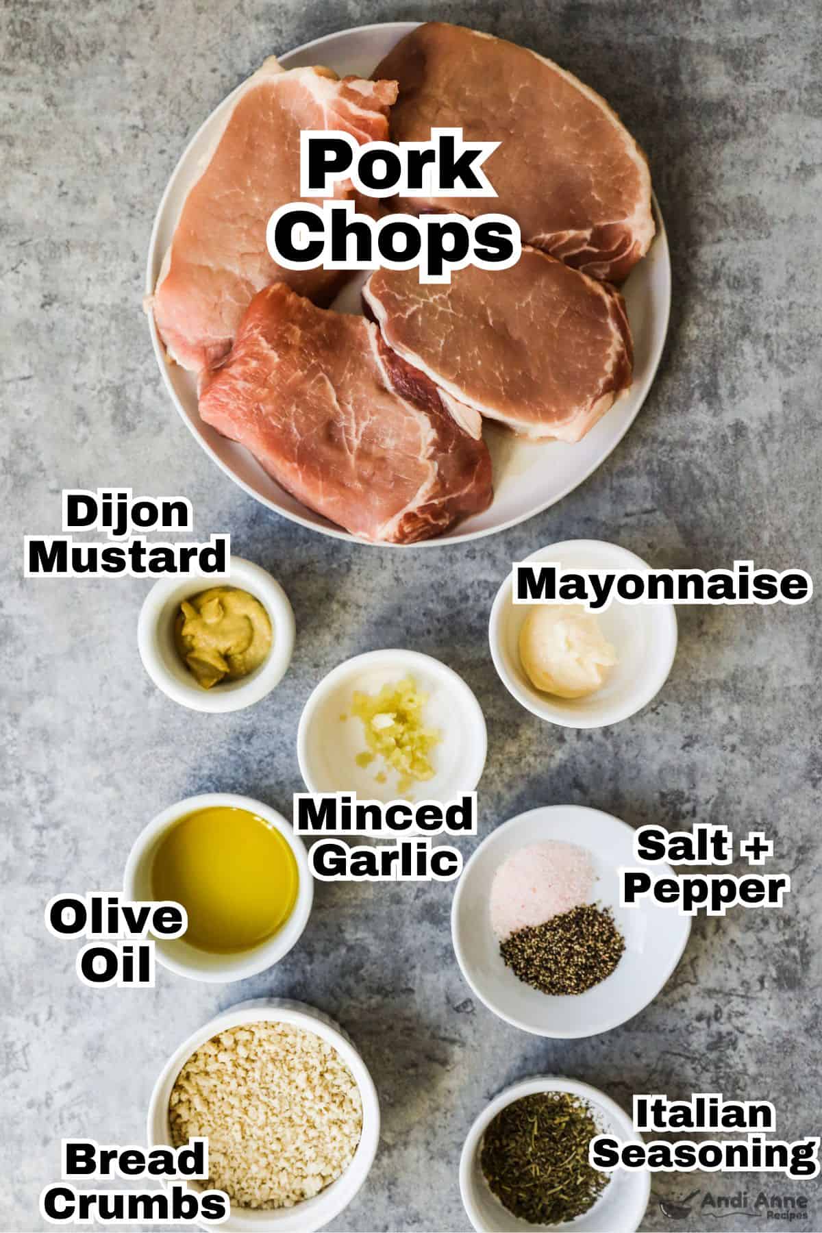 Recipe ingredients including plate of raw pork chops, bowls of dijon mustard, mayonnaise, minced garlic, olive oil, salt and pepper, bread crumbs and italian seasoning.