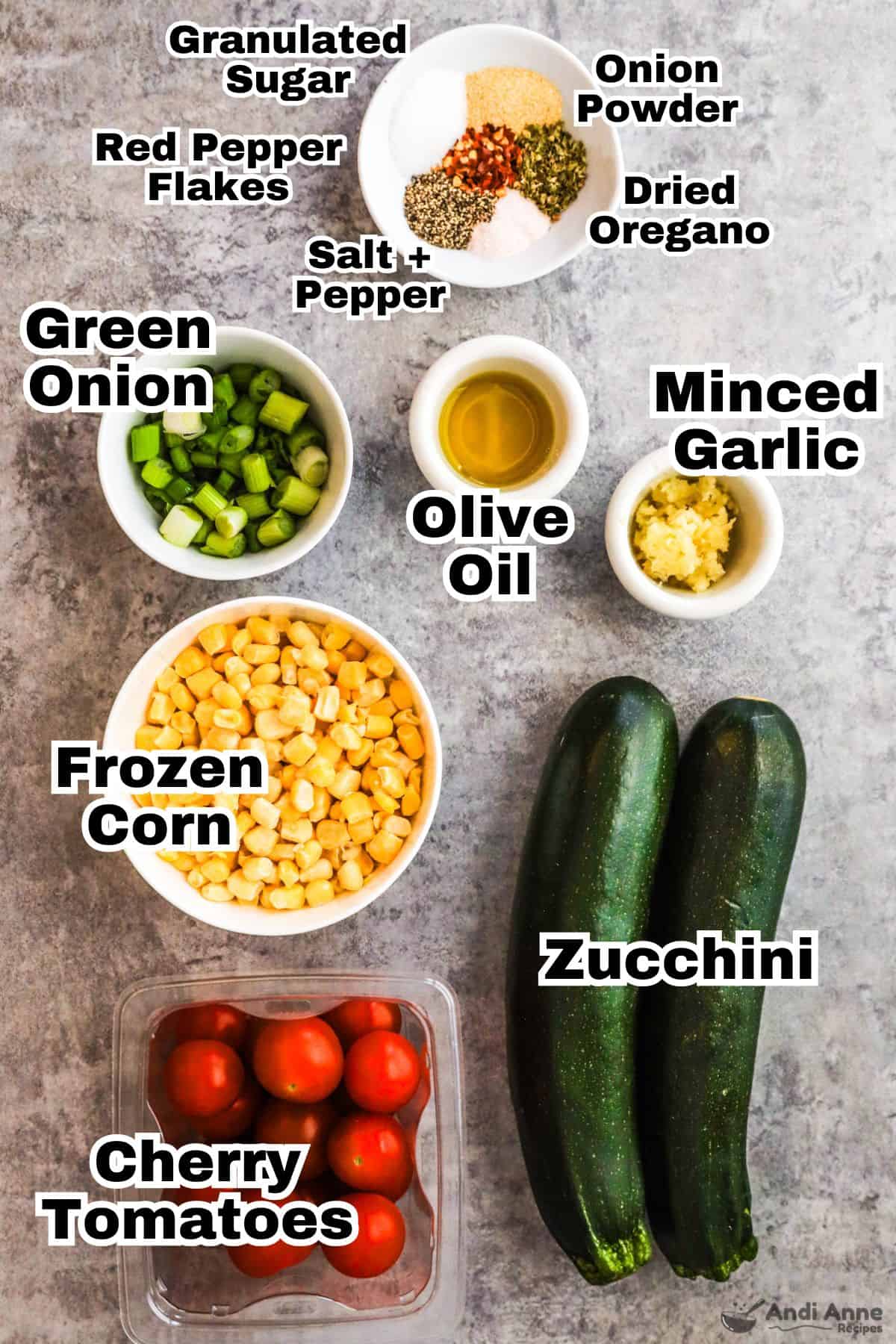 Recipe ingredients including bowl of spices, bowl of green onion, minced garlic, olive oil, corn and two zucchinis