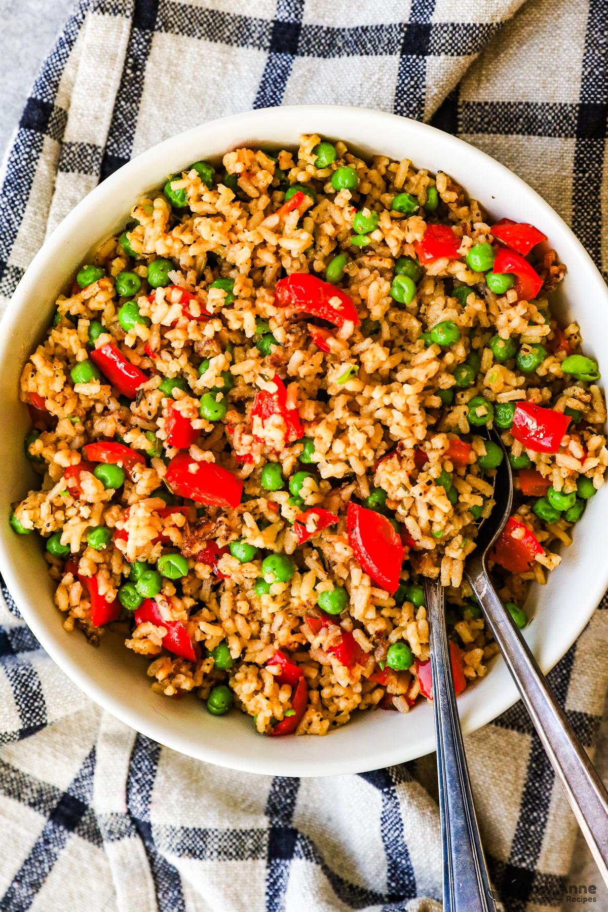 Bowl of rice with bell pepper and peas with two spoons