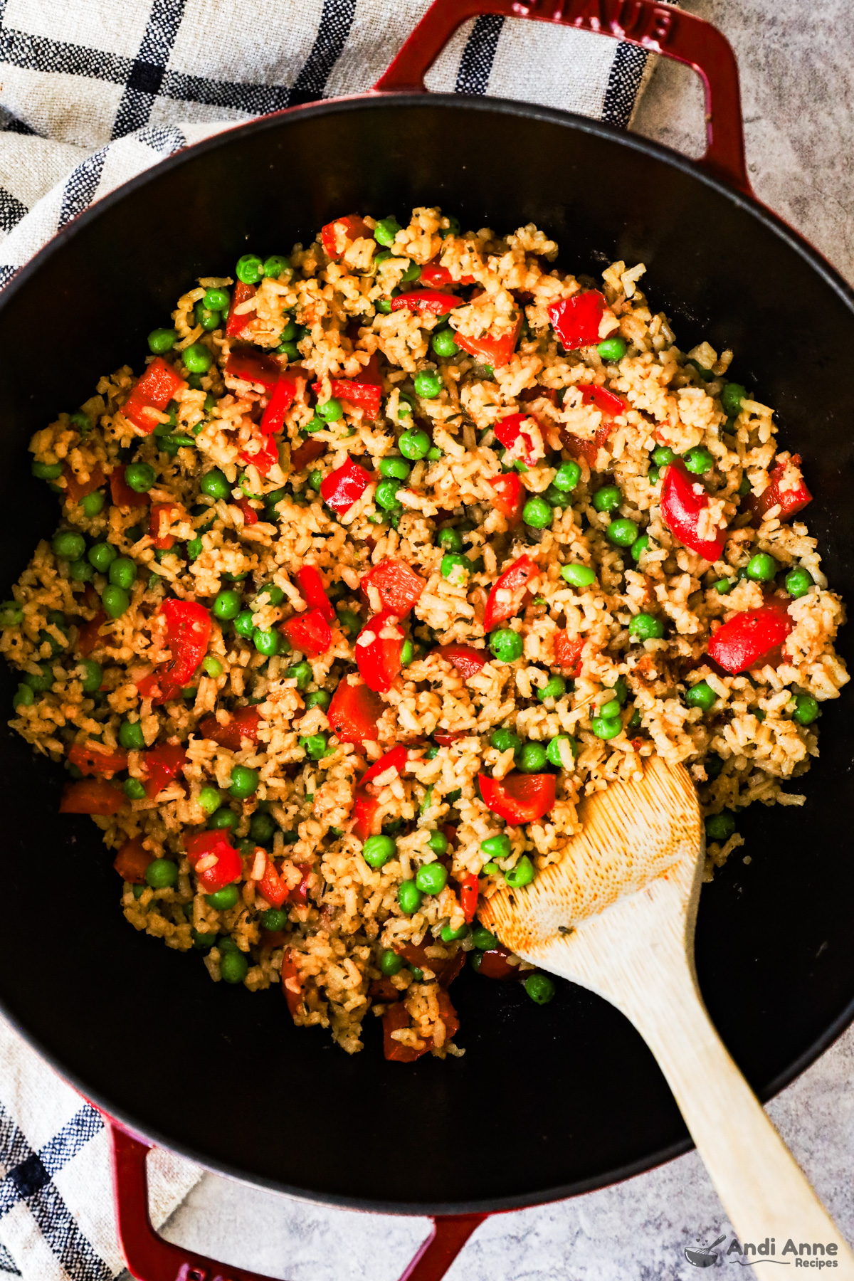 A pot with rice, chopped red bell pepper and peas