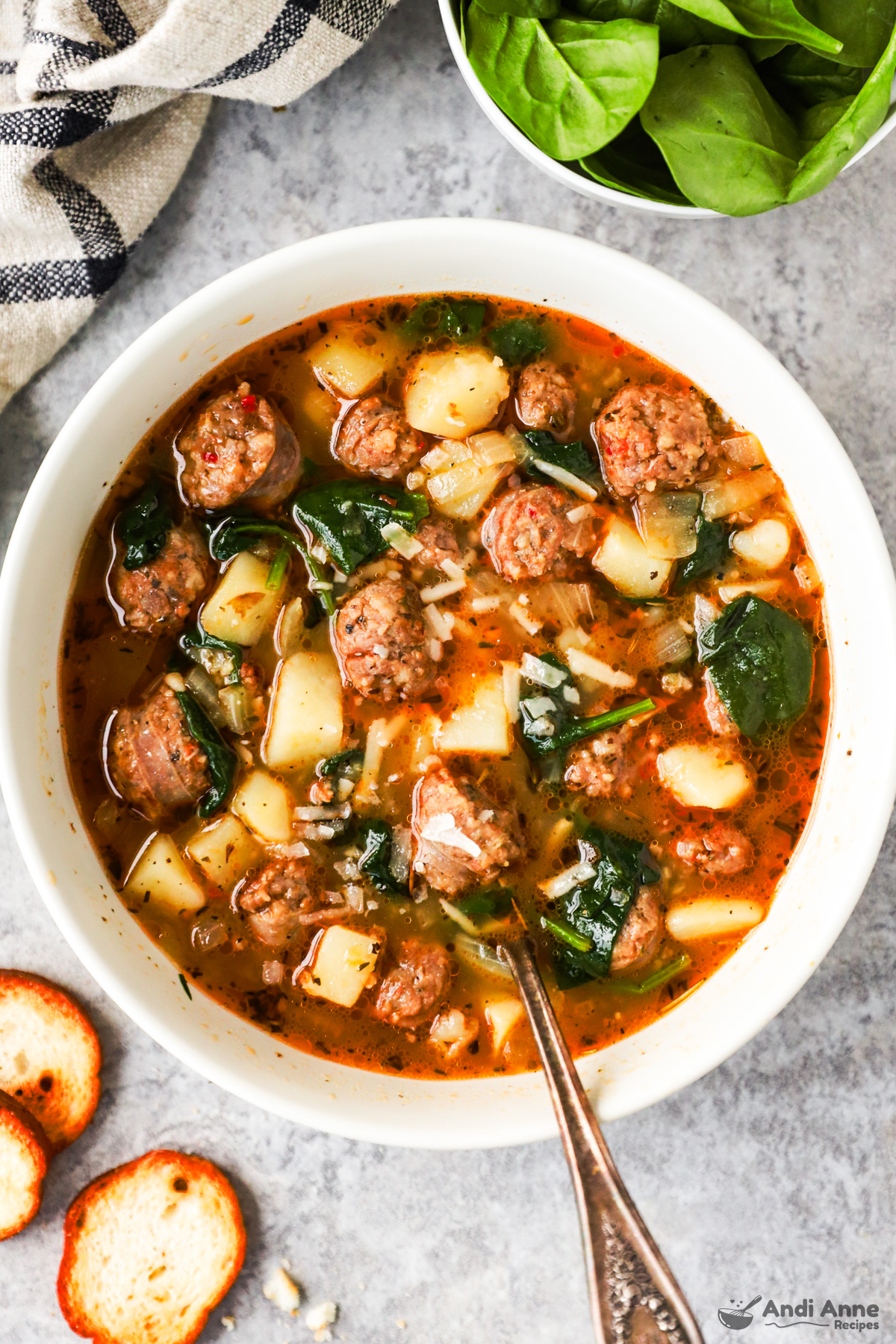 A bowl of sausage potato soup with spinach and grated parmesan