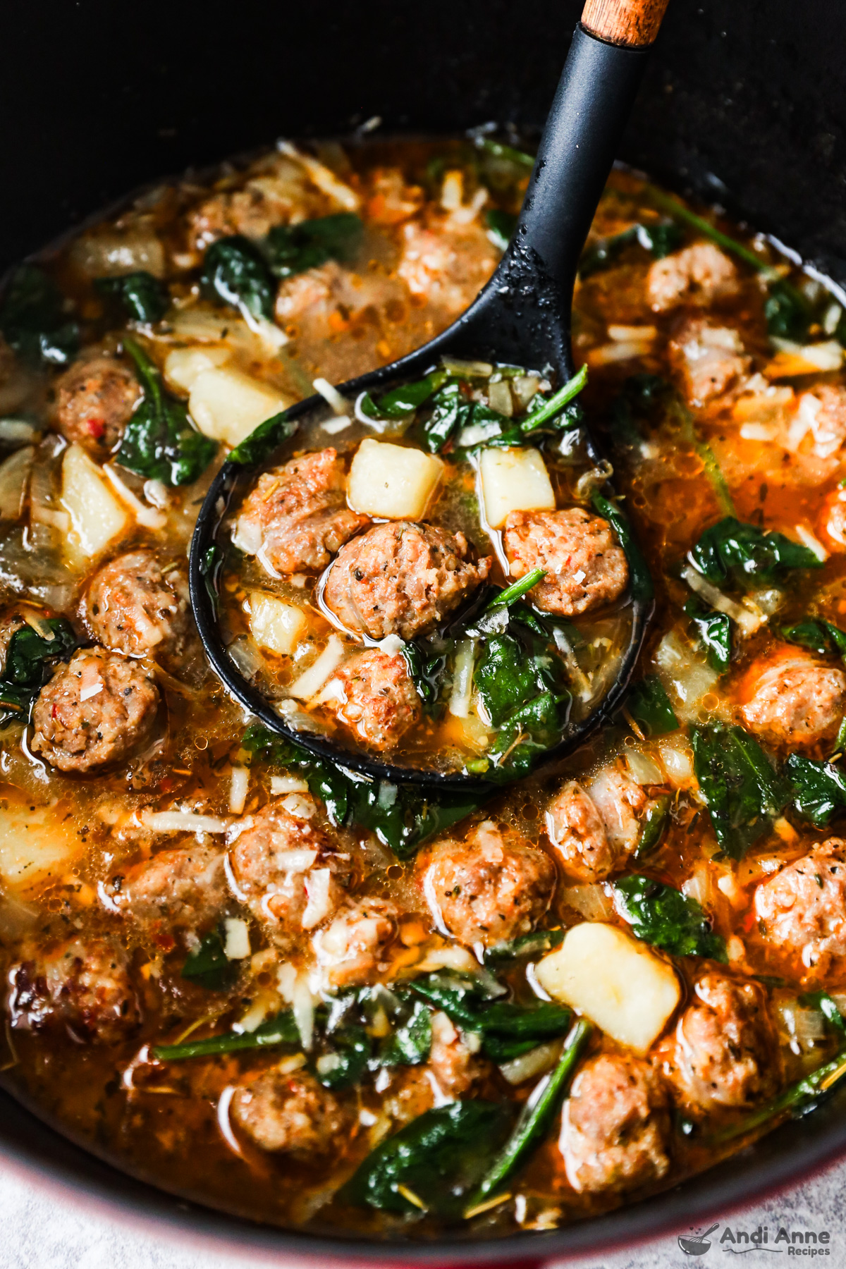 Close up of a soup ladle scooping some sausage potato soup