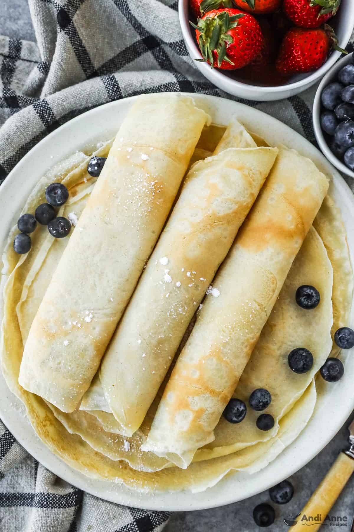 folded crepes over a stack of crepes and a bit of blueberries