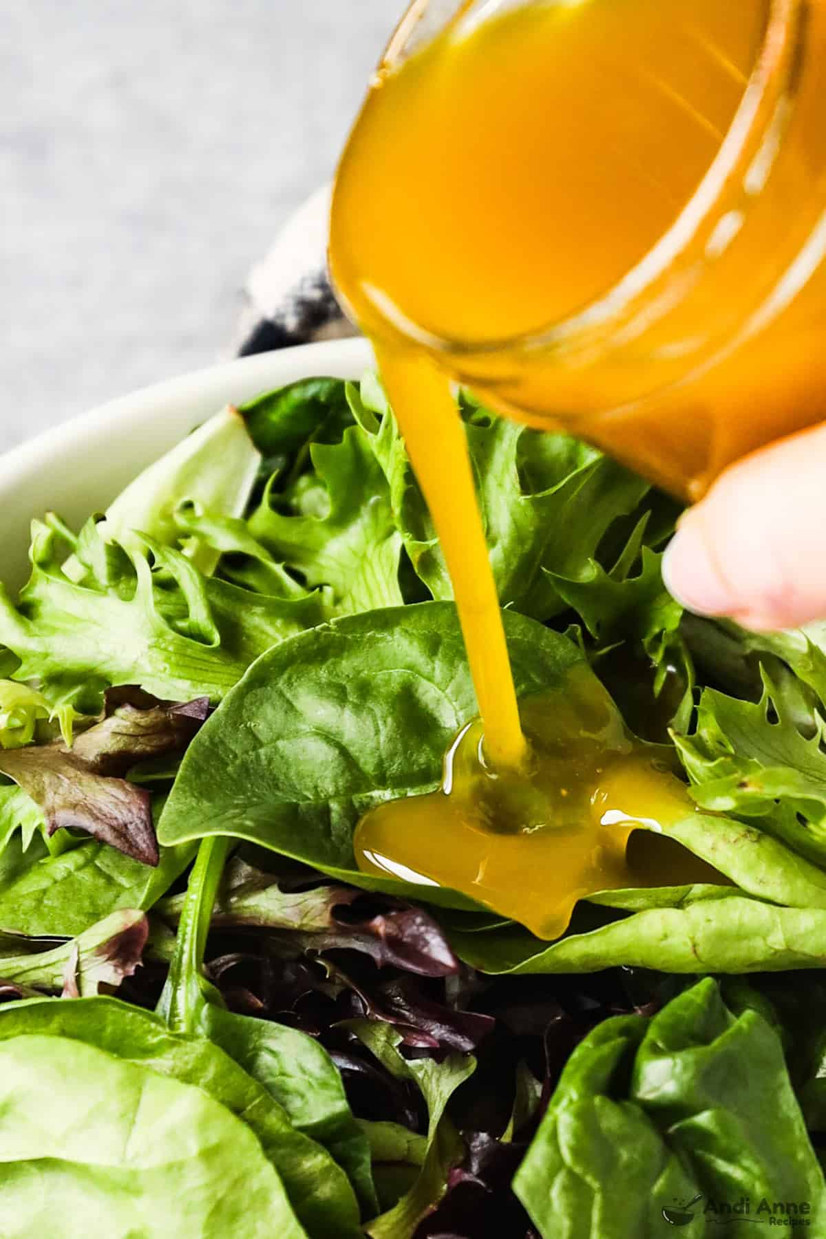 The classic vinaigrette is poured over a plate of salad greens.
