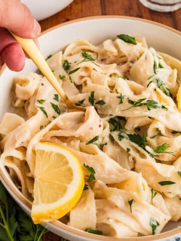 bowl of creamy pasta with a lemon wedge