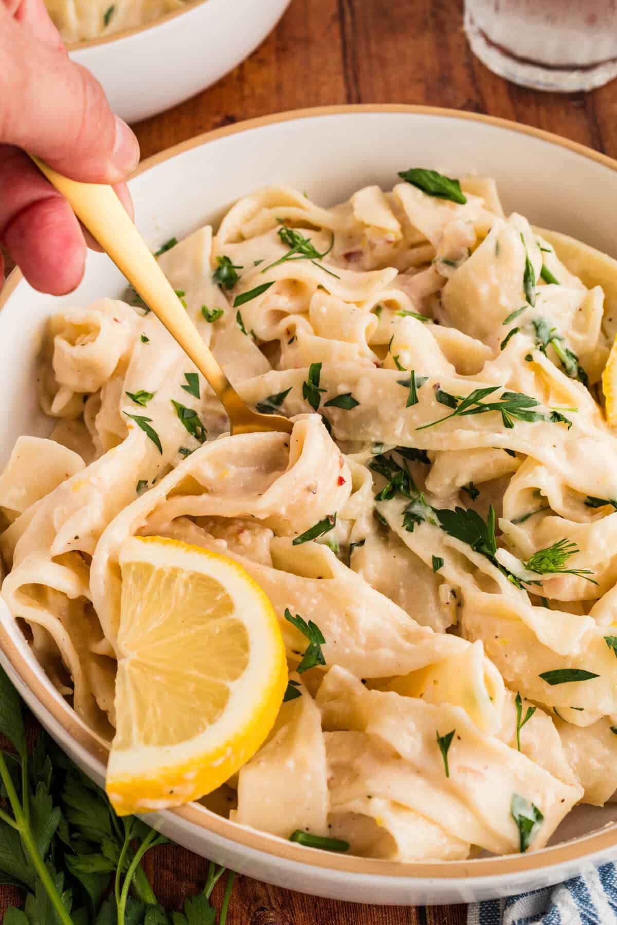 Close up of creamy lemon pasta with lemon wedge