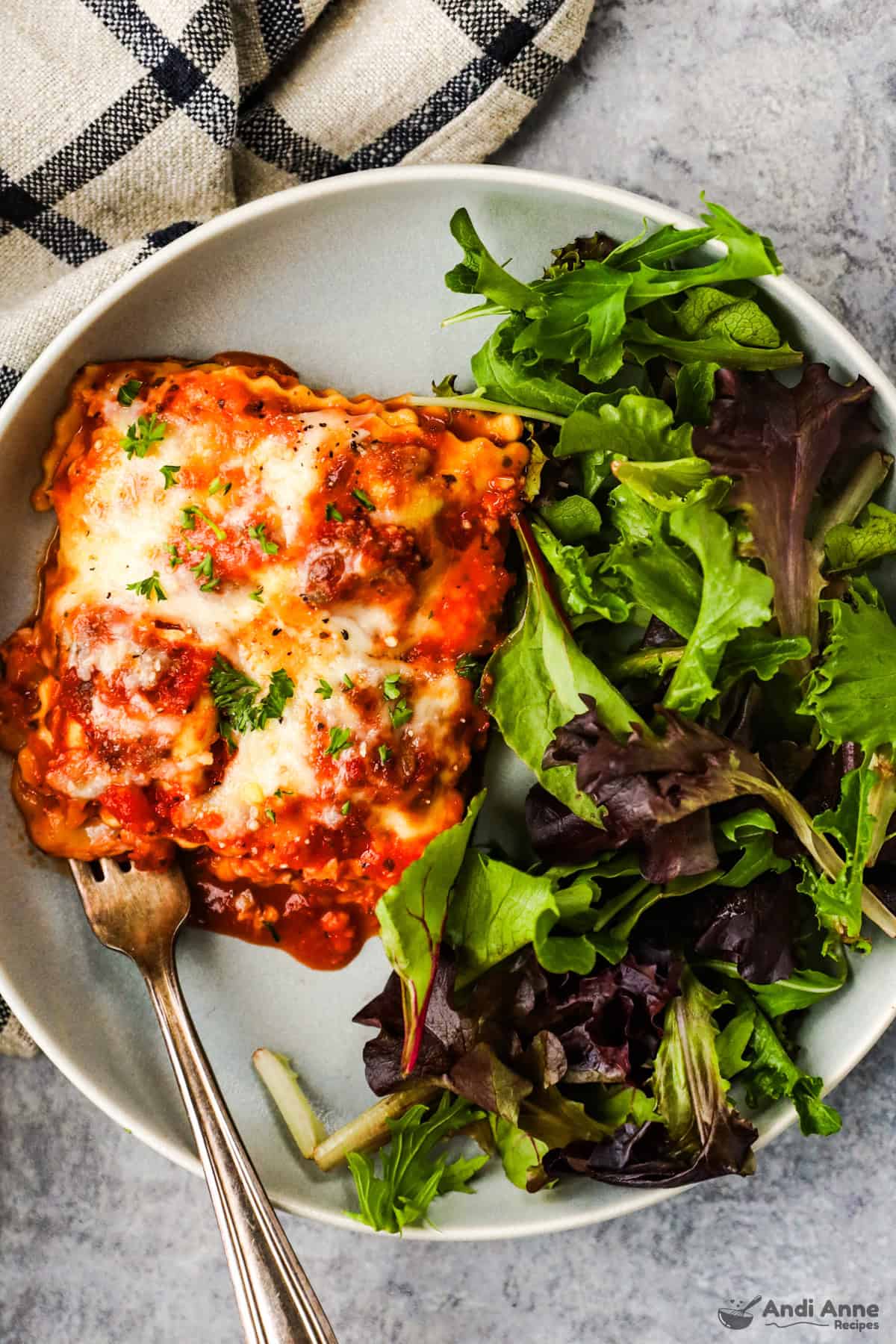 slice of ravioli lasagna with mixed greens on a plate