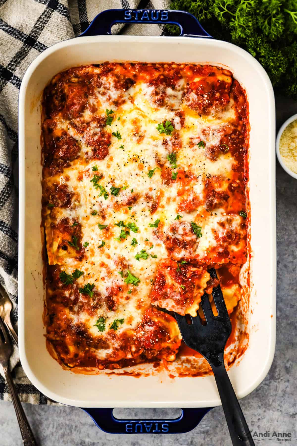 A casserole dish with ravioli lasagna and a spatula