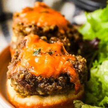 Two cheeseburger tarts on a plate and a side of salad.