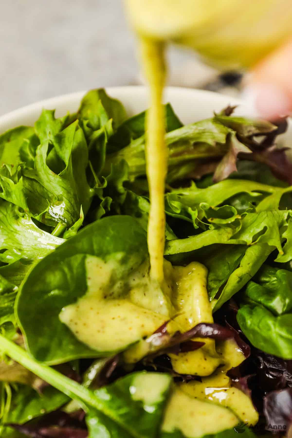 Kiwi citrus dressing is poured onto a mixed greens salad.
