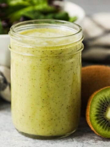 A mason jar full of kiwi citrus salad dressing.