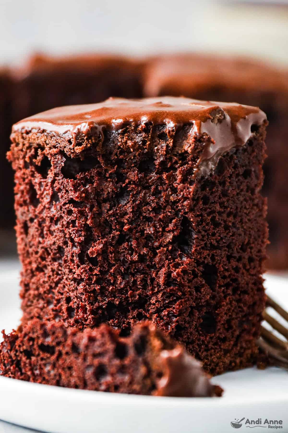 A slice of old-fashioned chocolate cake on a plate with a fork.