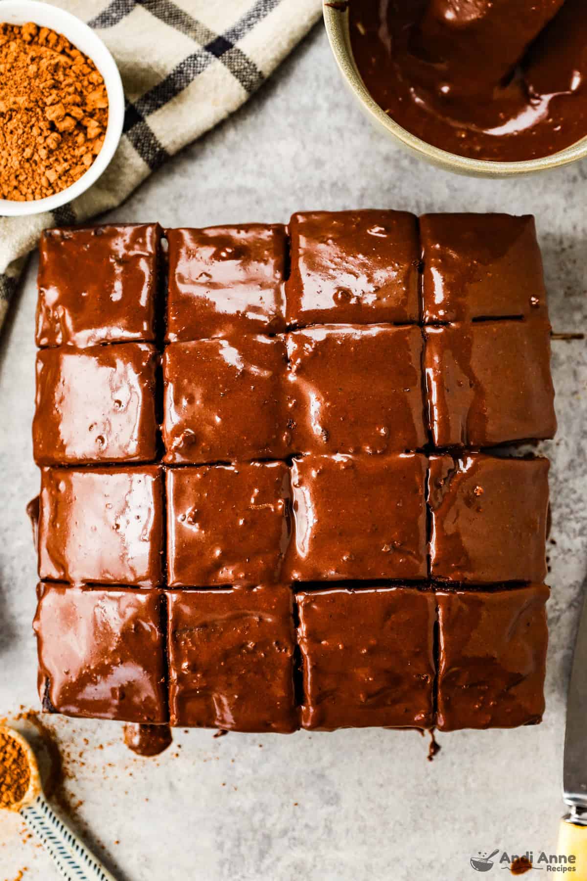 Frosted old-fashioned chocolate cake sliced into 16 square pieces.