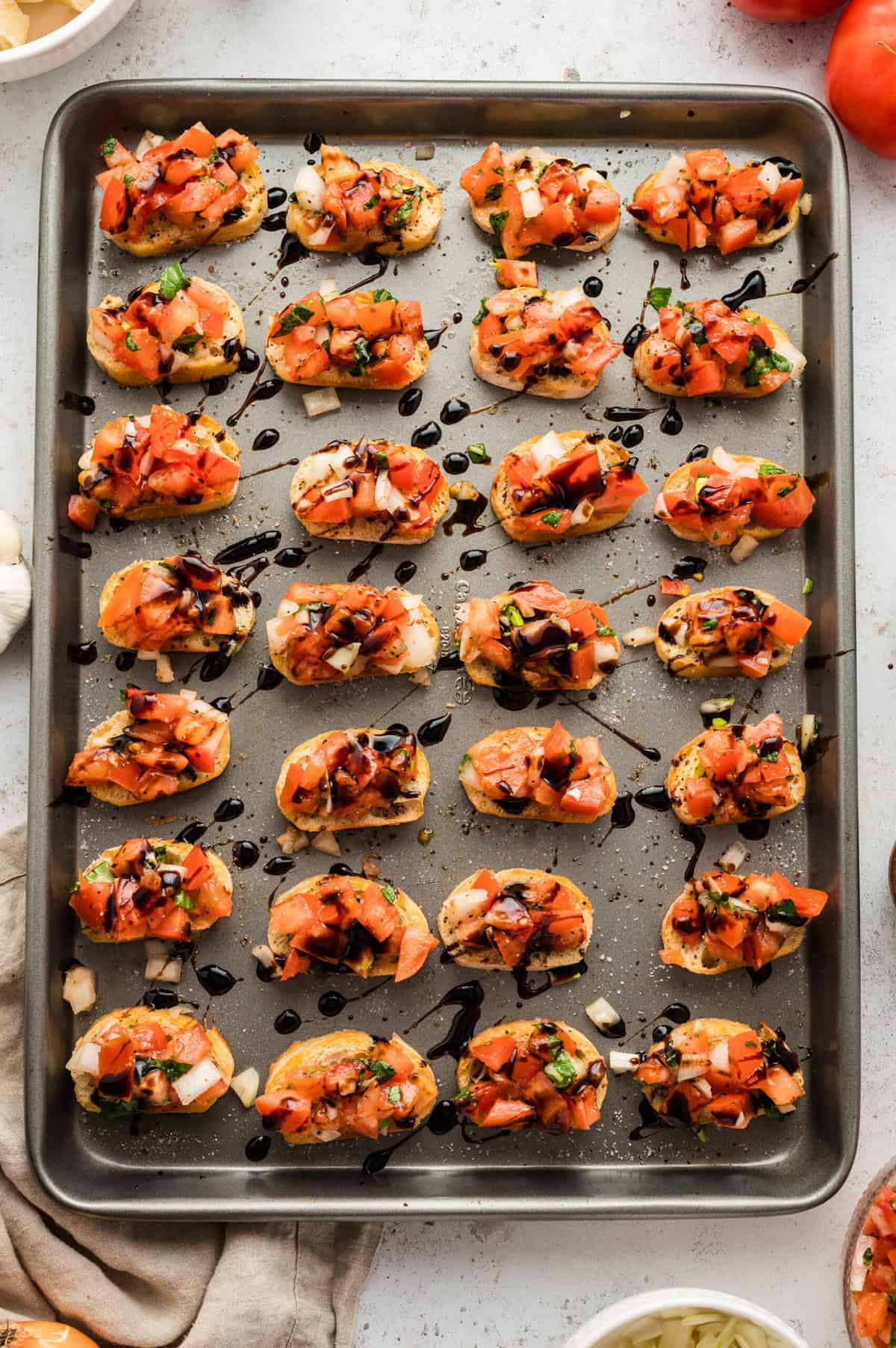 Tomato bruschetta with a balsamic glaze on a baking sheet.