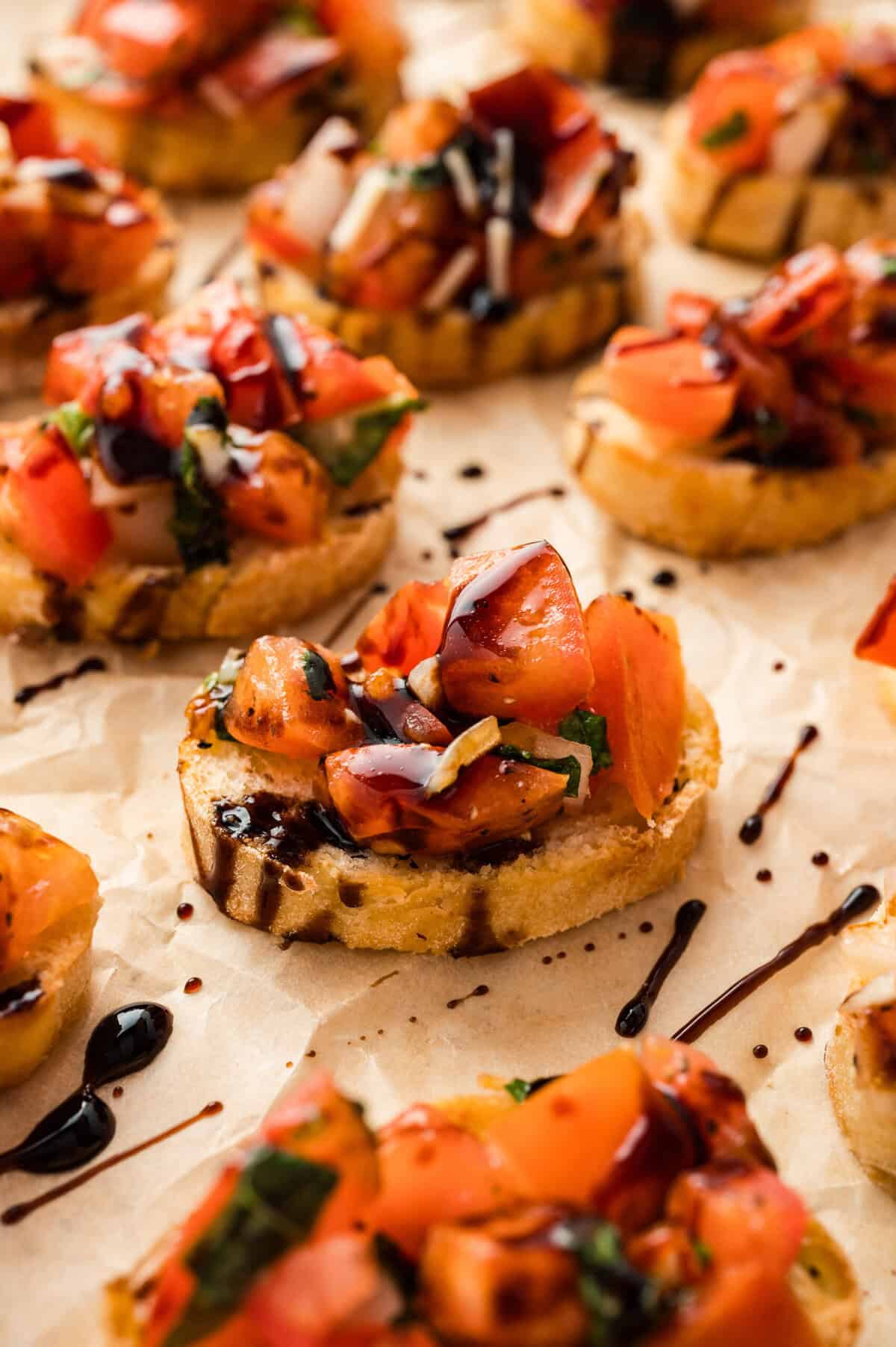 Small slices of toasted baguette topped with tomato bruschetta and balsamic glaze.