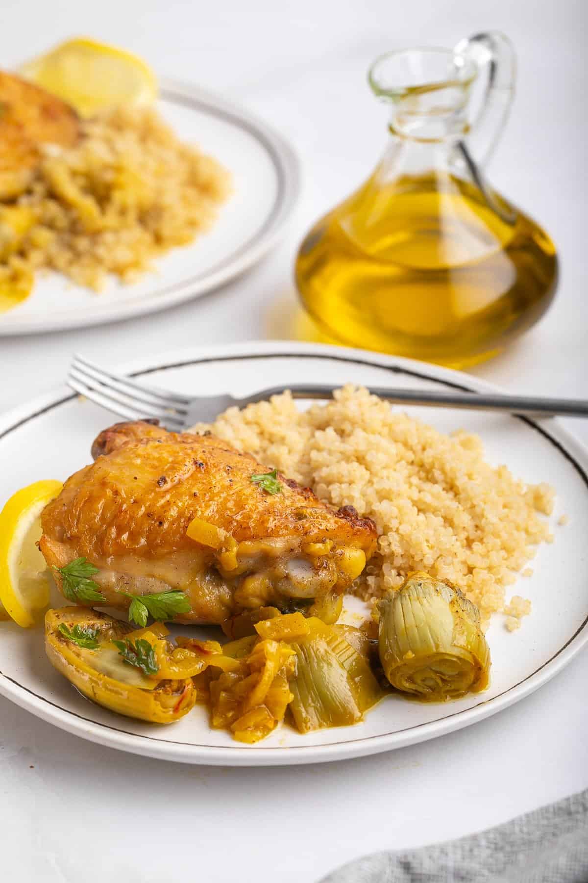 Artichoke chicken is served on a plate with a side of couscous.