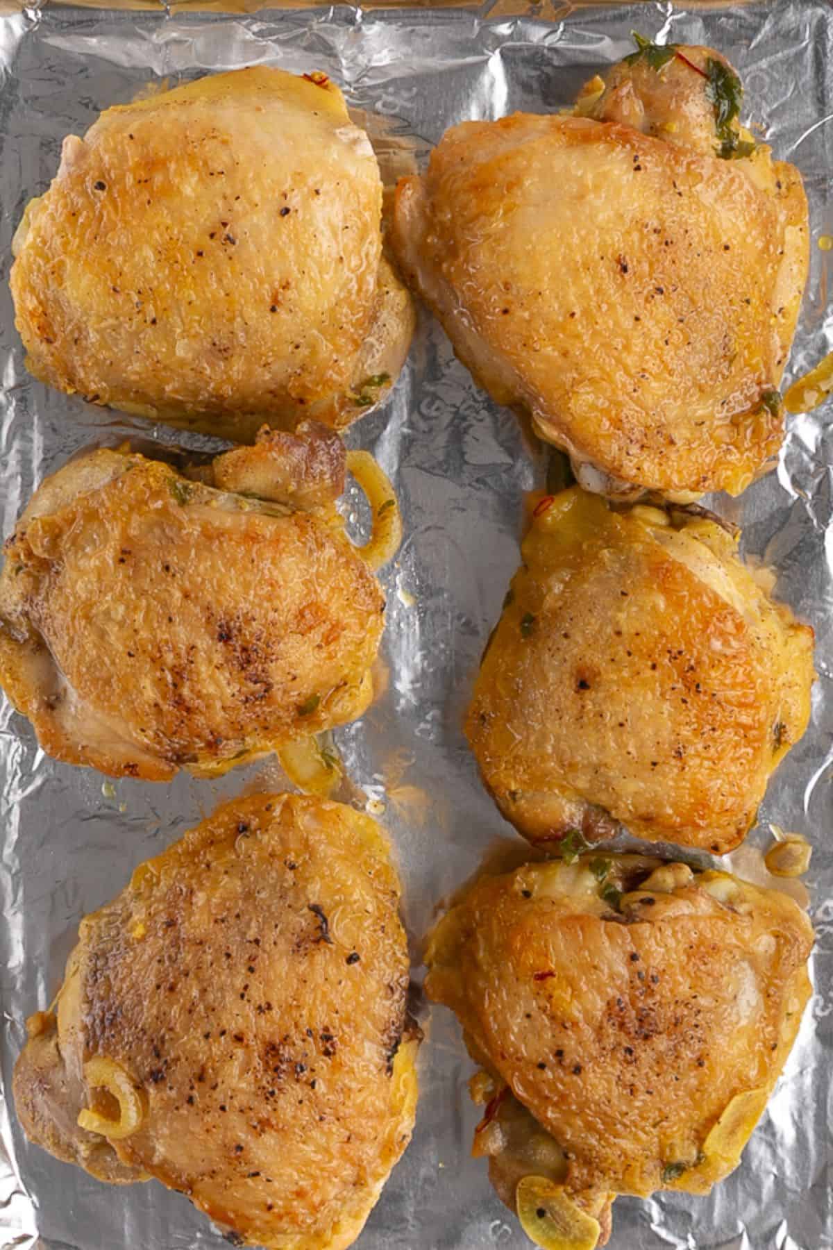 The chicken thighs are on a foil-lined baking tray.