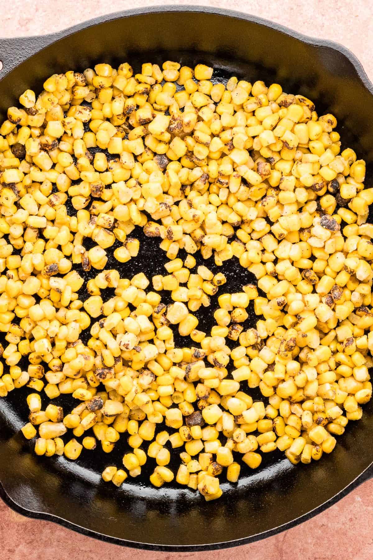 The frozen fire-roasted corn is added to the cast-iron skillet.