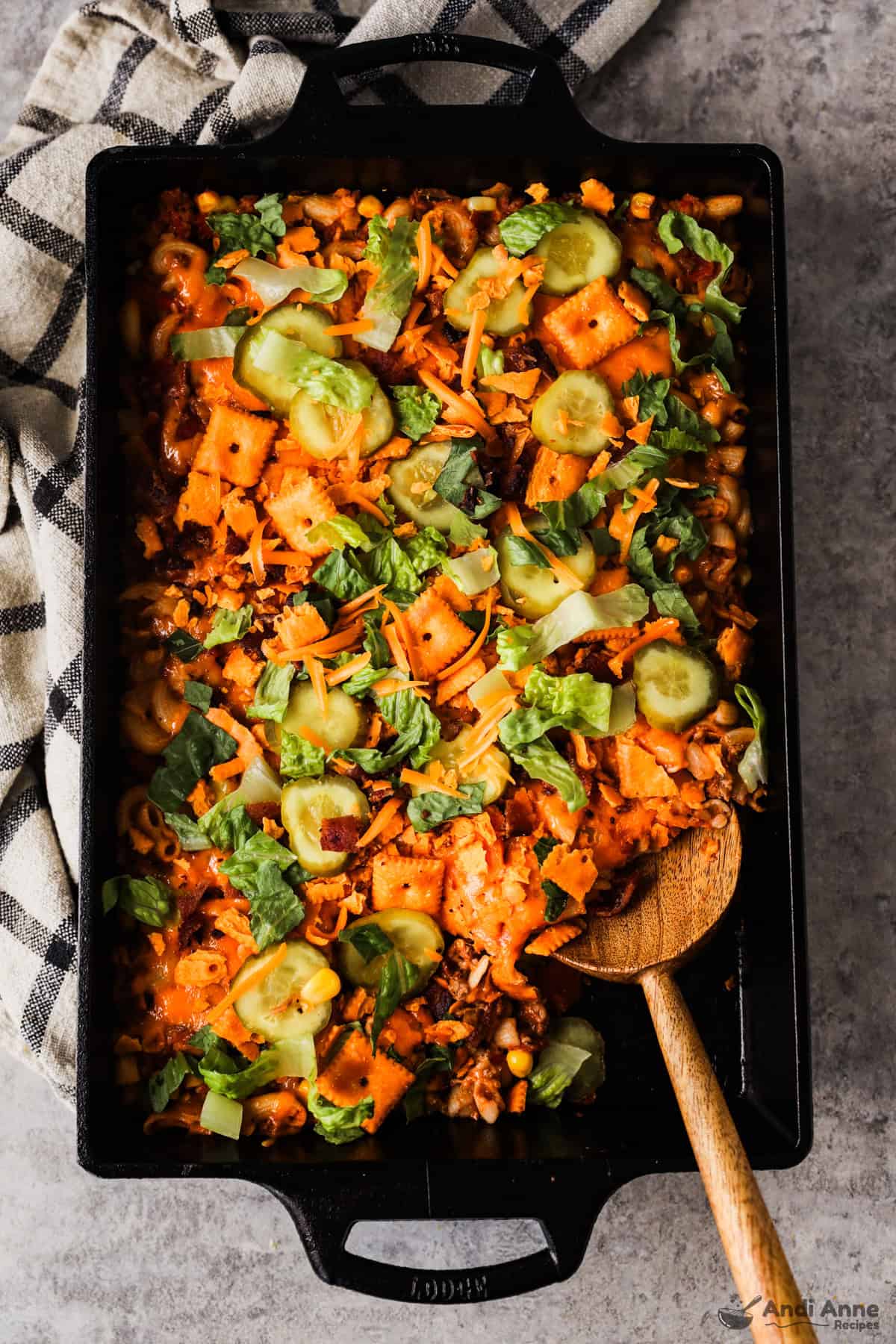 A pan of cheeseburger casserole topped with pickle slices and lettuce.