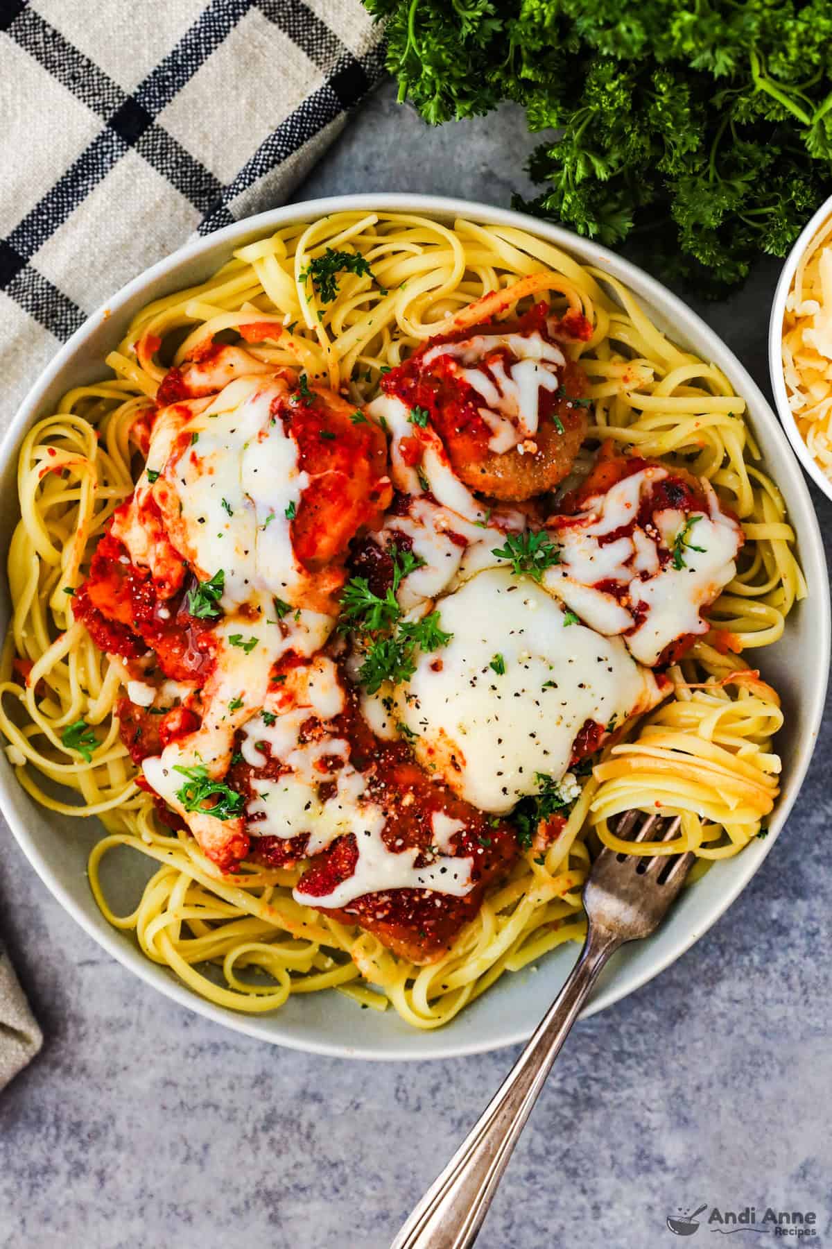 Bowl of chicken nuggets covered in sauce and cheese over noodles