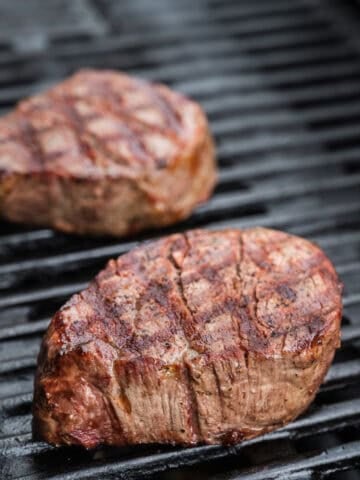 Two filet mignon steaks on a grill.