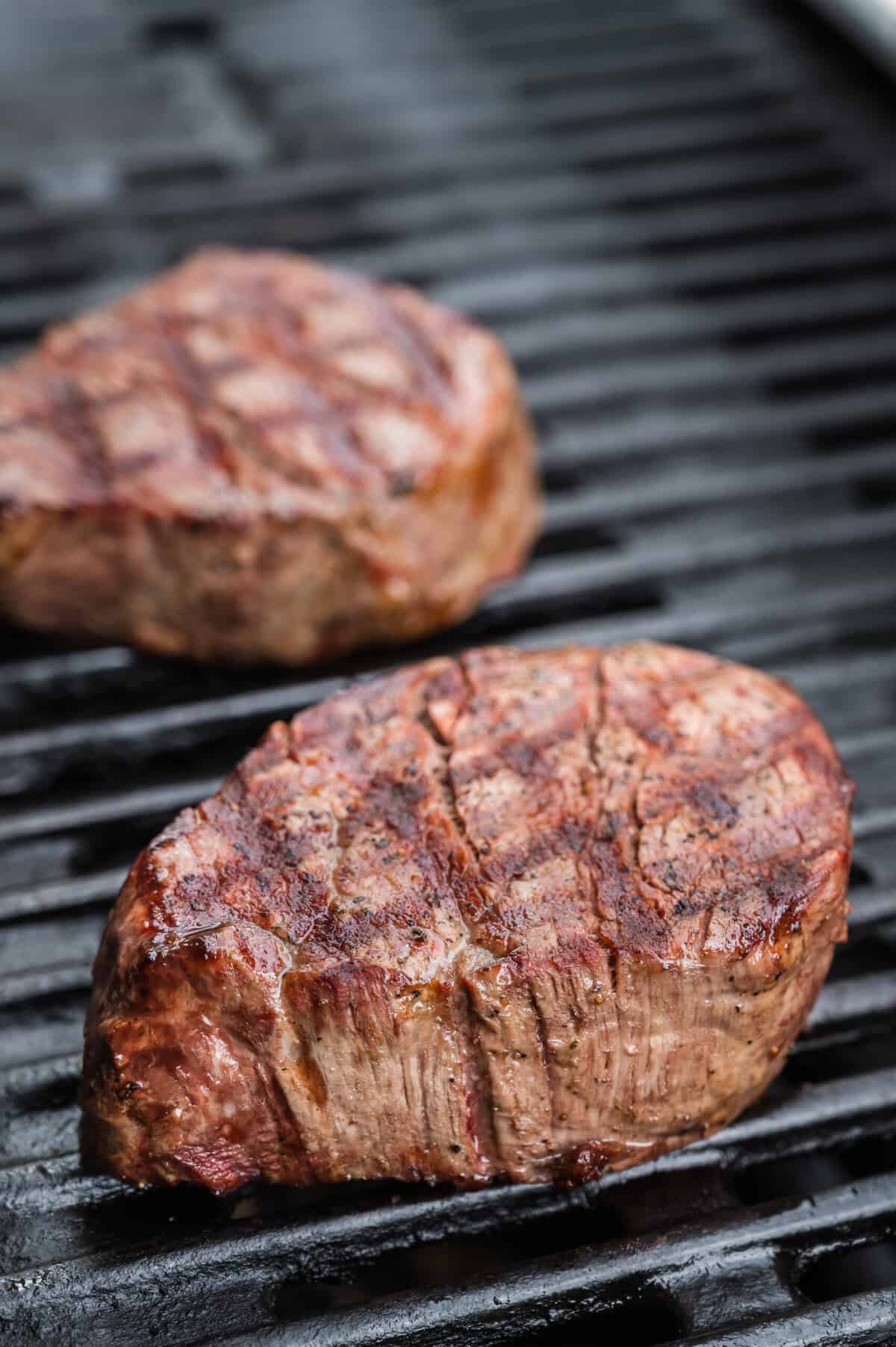 Two filet mignon steaks on a grill.