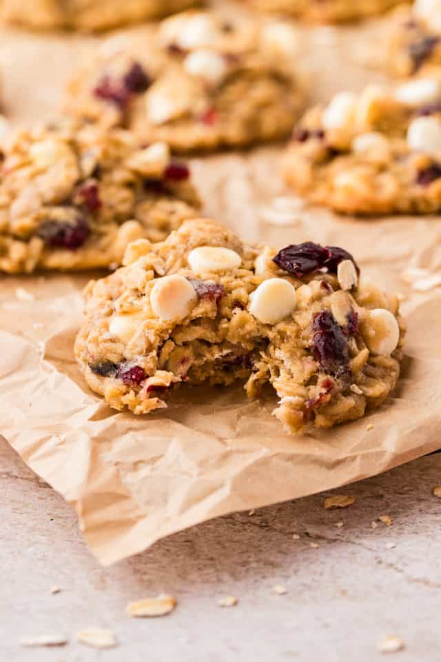 An oatmeal cranberry cookie is split in half on a baking sheet.