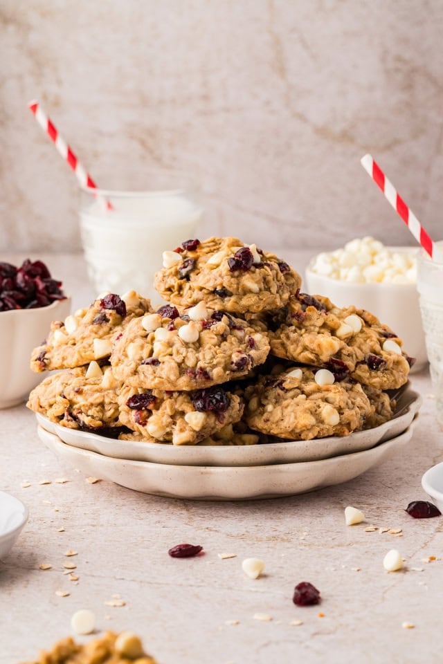A plate filled with oatmeal cranberry cookies and a glass of milk in the background.